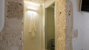 Een badkamer met een stenen muur, een glazen douchedeur en een handdoek aan de wand.