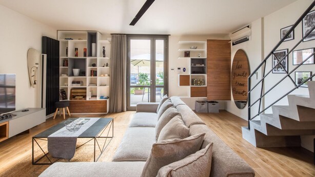 A modern living room with a sofa, a TV, a bookshelf, and a staircase. - Casa con Giardino all ex Fabbrica di Pomodoro by Wonderful Italy (Palermo)