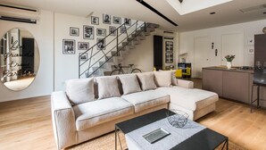 A modern living room with a light-colored sectional sofa, a black coffee table, and a staircase with black railings. - Casa con Giardino all ex Fabbrica di Pomodoro by Wonderful Italy (Palermo)
