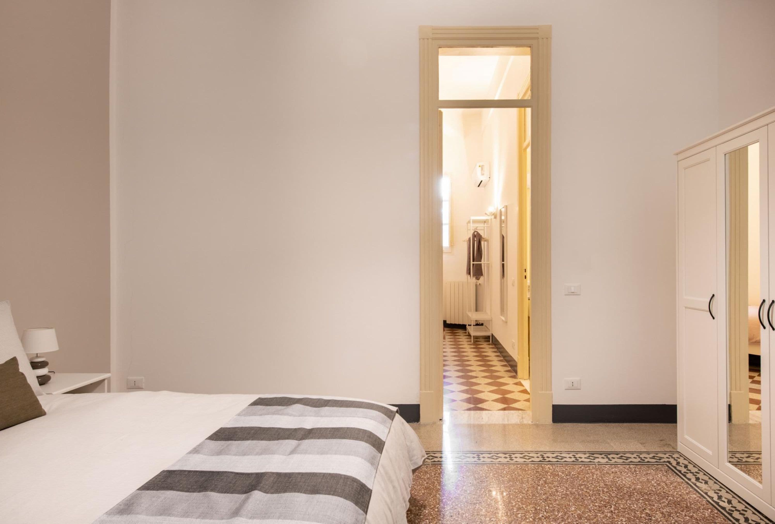 A bedroom with a bed, a wardrobe, and a checkered floor.
