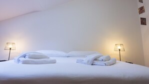 A hotel room with a neatly made bed, two bedside lamps, and a skylight. - Casa Garisenda by Wonderful Italy (Bologna)