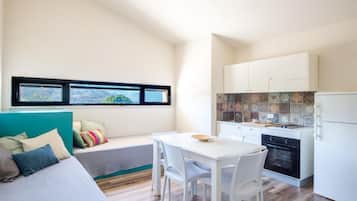 Un espacio habitable compacto con kitchenette, comedor y cama con vistas.