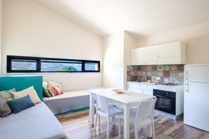 A compact living space with a kitchenette, a dining area, and a bed with a view.