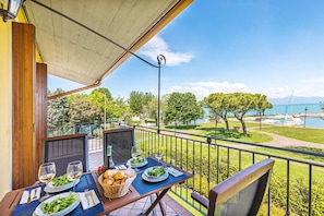 A balcony with a table set for dining, overlooking a marina with boats and trees. - I Mosaici 3 in Sirmione (Sirmione)