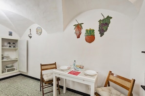 A dining area with a white table, two wooden chairs, and a white cabinet with dishes.