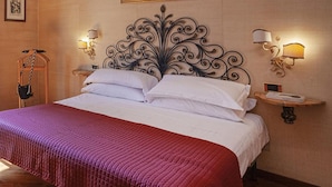 Una camera d'albergo con un letto, una testiera decorativa, due lampade a parete e un quadro incorniciato sopra il letto.