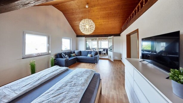 Een moderne slaapkamer met een groot bed, een bank en een televisie.