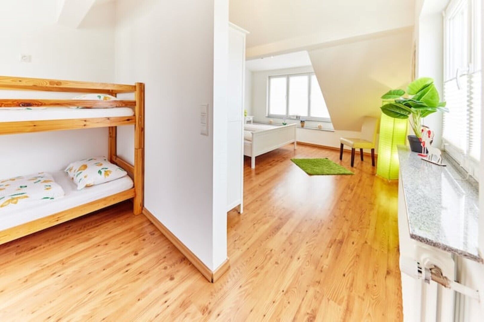 Una habitación con literas, un escritorio y una ventana con una planta.