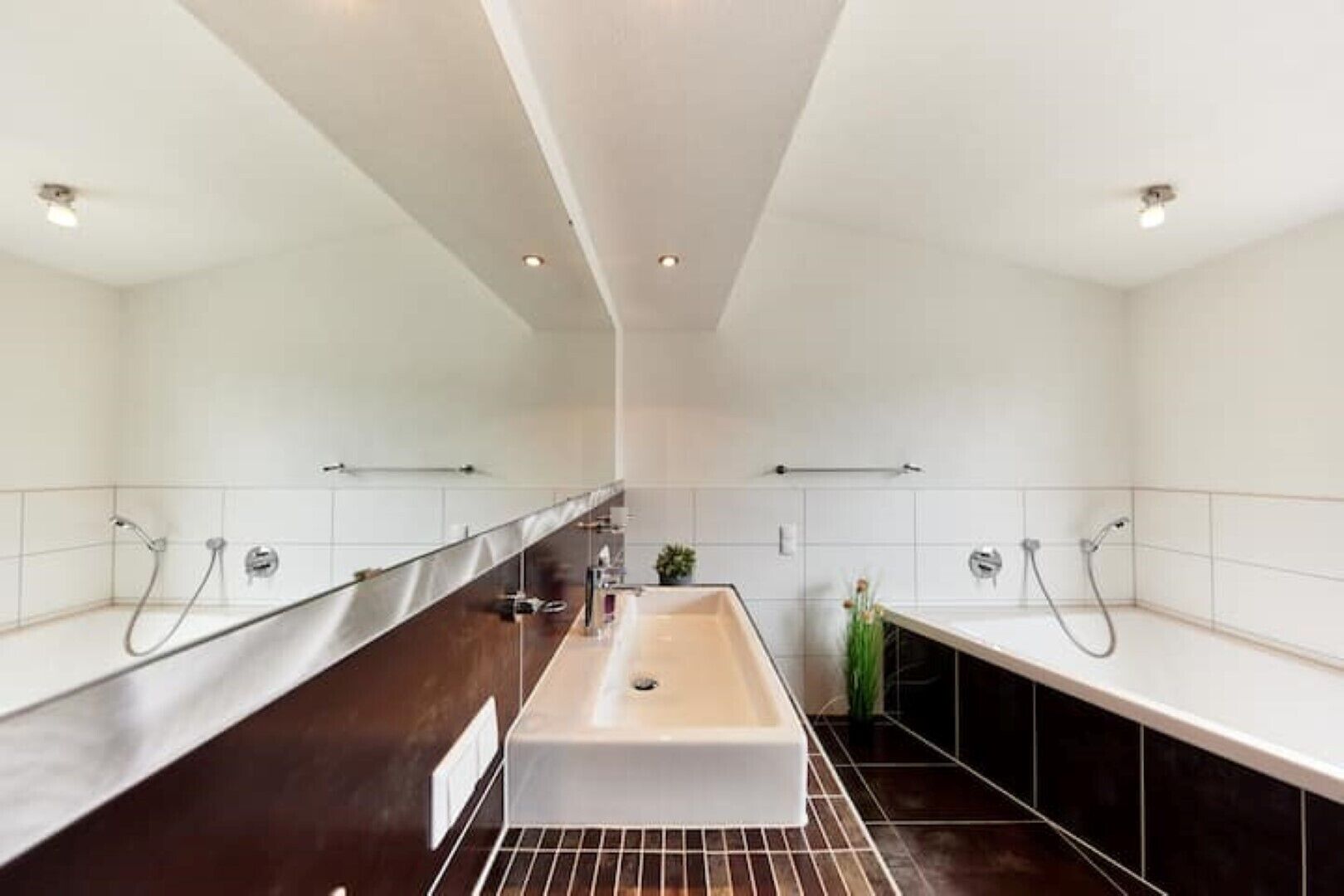 A modern bathroom with a central sink, two showerheads, and a towel rack.