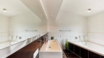 A modern bathroom with a central sink, two showerheads, and a towel rack.