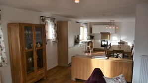 Un espacio habitable compacto con un mueble de madera, una mesa de comedor y una zona de cocina.