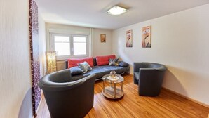 Ein modernes Wohnzimmer mit einer Couch, zwei Sesseln und einem Couchtisch.