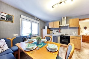 A compact kitchen with wooden cabinets, a stainless steel range hood, and a dishwasher.