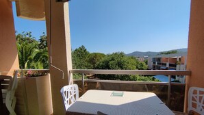A balcony with a table and chairs, overlooking a scenic view of trees and buildings.