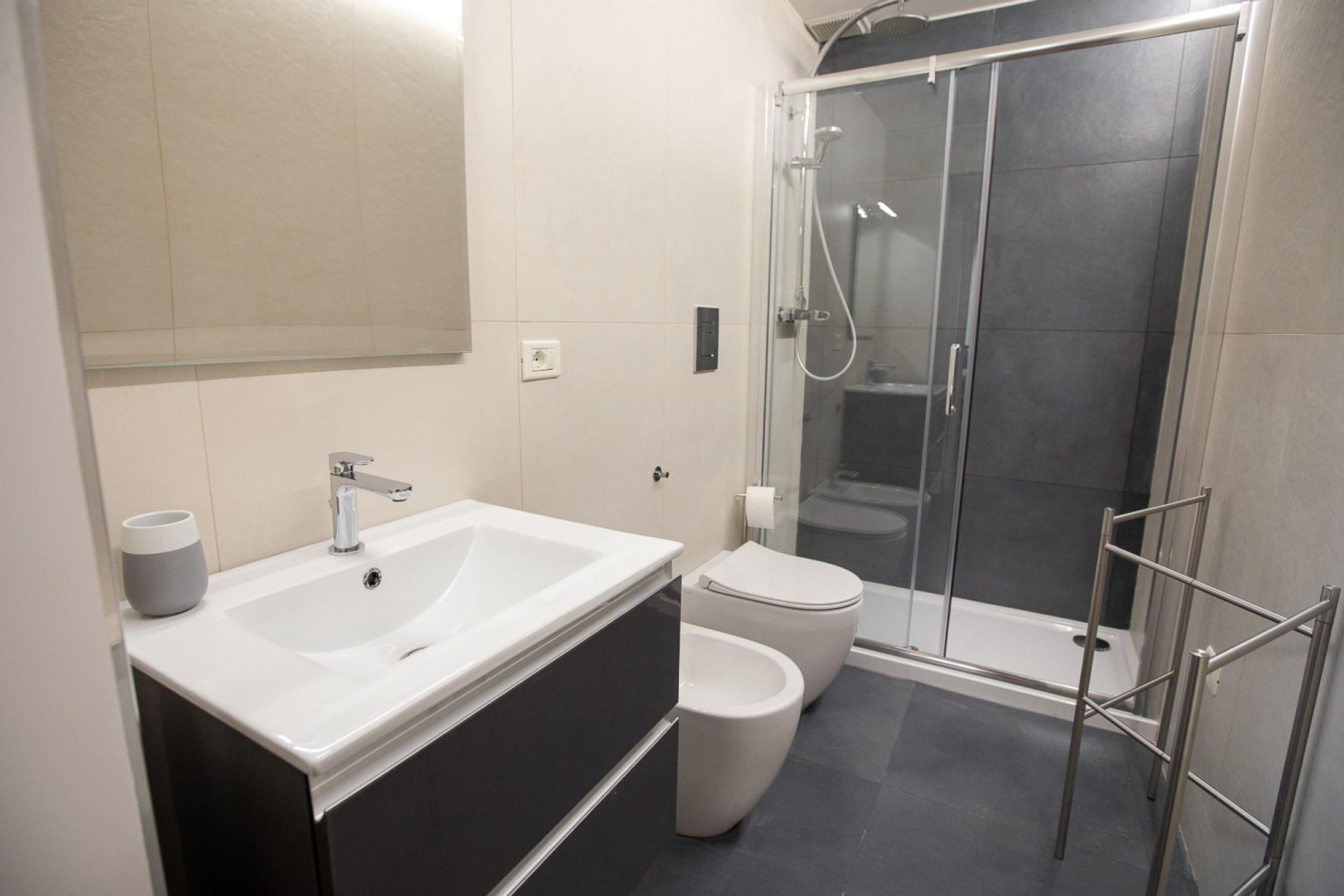 A modern bathroom with a white sink, toilet, and glass-enclosed shower.
