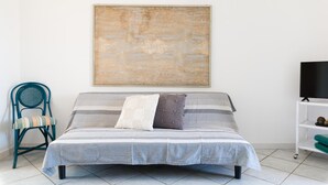 A bedroom with a bed, a chair, a TV, and a large abstract painting on the wall. - White Sea - Villetta Ariel (Carovigno)