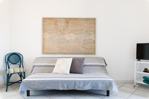 Relax in this serene bedroom with a single bed, abstract art, and a comfortable chair.