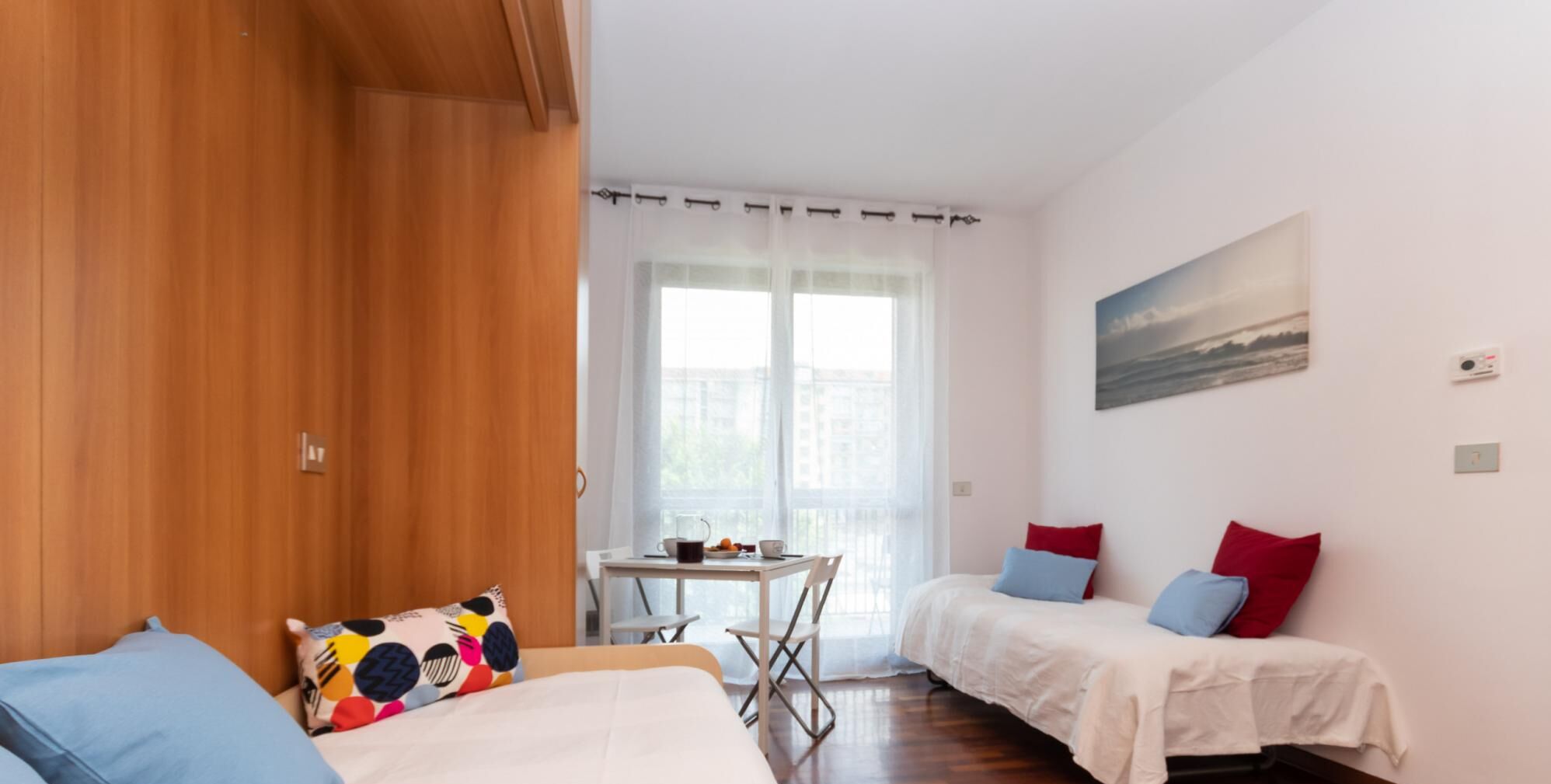 Een kamer met twee bedden, een tafel met ontbijtartikelen en een raam met dunne gordijnen.