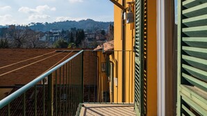 A balcony with a view of a hillside and distant buildings.
