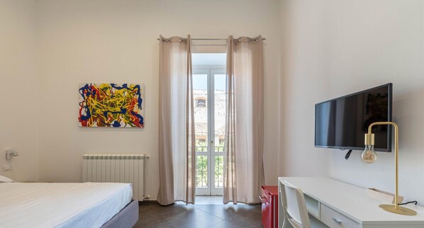 A bedroom with a bed, a TV, a painting, and a window with curtains. - Apartment La Cala by Wonderful Italy (Palermo)