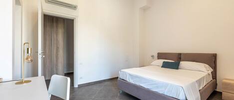 A bedroom with a bed, a desk, and a chair.