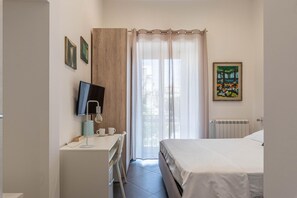 A bedroom with a bed, a desk with a computer, a chair, and a window with curtains. - Apartment La Cala by Wonderful Italy (Palermo)