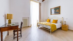 Une chambre à coucher avec un lit, un bureau, une chaise, un radiateur et un tableau accroché au mur.