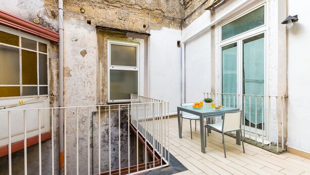 Un balcon avec une rambarde en métal, une table avec des chaises et une fenêtre donnant sur un beau paysage.
