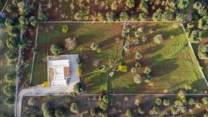 An aerial view of a property with a rectangular building, surrounded by a mix of forested areas and open fields.