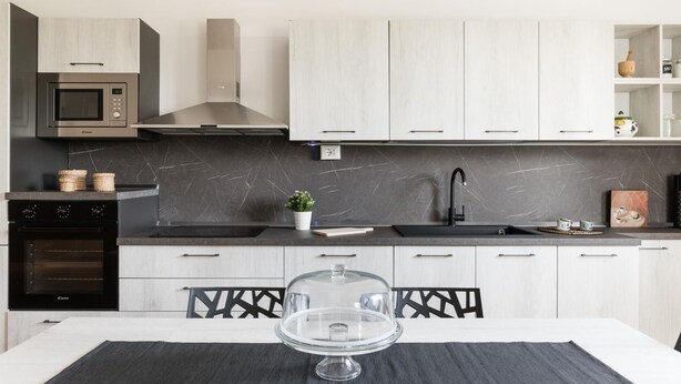 A modern kitchen with a microwave, oven, and stove. There is a sink with a faucet, and a dining table with chairs.
