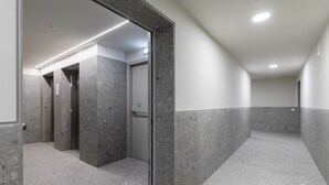 A corridor with a marble floor and walls, leading to an elevator. - Casa Bassani con Terrazzo by Wonderful Italy (Bologna)