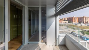 A modern apartment with a balcony, a sliding glass door leading to a room, and a view of a cityscape with buildings and parked cars. - Casa Bassani con Terrazzo by Wonderful Italy (Bologna)