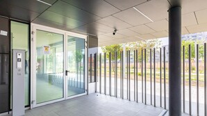 A modern entrance with a glass door, a keypad entry system, and a view of the outside through metal railings. - Casa Bassani con Terrazzo by Wonderful Italy (Bologna)