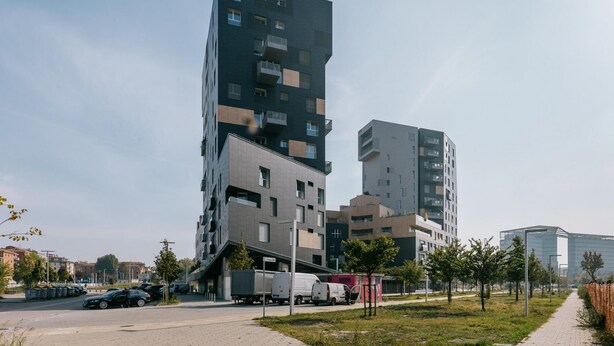 A modern multi-story building with a mix of residential and commercial spaces, featuring balconies and a parking area with vehicles. - Casa Bassani con Terrazzo by Wonderful Italy (Bologna)