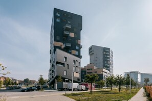 A modern multi-story building with a mix of residential and commercial spaces, featuring balconies and a parking area with vehicles. - Casa Bassani con Terrazzo by Wonderful Italy (Bologna)