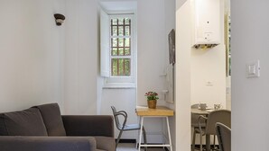 A compact living space with a sofa, a small table with chairs, a window with a view, and a wall-mounted phone. - Cozy Holiday Home in Camogli (Camogli)