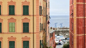A coastal building with multiple windows and balconies, overlooking a marina with boats. - Cozy Holiday Home in Camogli (Camogli)