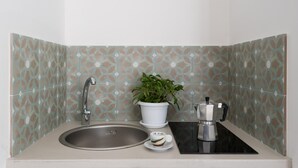 A kitchen with a sink, a potted plant, and a coffee maker. - Dioniso Smart Suite With Balcony by Wonderful Italy (Syracuse)