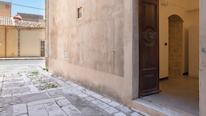 Un edificio con un acceso empedrado de piedra, una puerta de madera y una ventana pequeña.