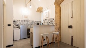 Una cocina compacta con una isla central, taburetes de bar, un refrigerador y una estufa.