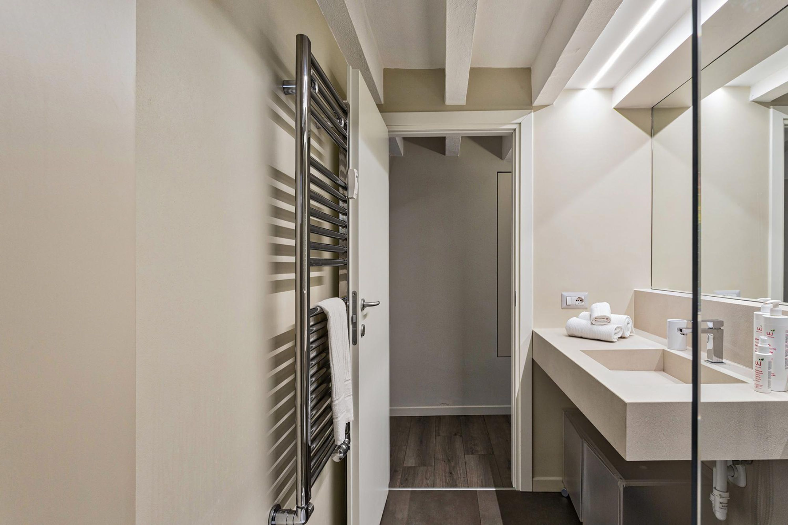 Un bany modern amb una cabina de dutxa de vidre, un lavabo blanc i un suport per a tovalloles.