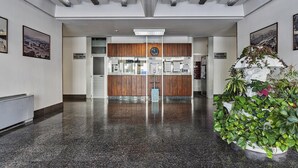 A lobby with a polished granite floor, wooden paneling, and a large potted plant. - Deluxe Apartment - Grey by Wonderful Italy (Genoa)