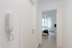 A hotel room with a white telephone, a bed, a TV, and a window with curtains. - Studio Glicine by Wonderful Italy (Turin)