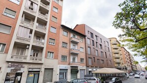 A multi-story residential building with balconies and a row of parked cars in front. - Studio Glicine by Wonderful Italy (Turin)