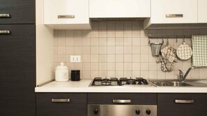 Una cucina moderna con mobili scuri, piano cottura a gas, forno e lavello in acciaio inossidabile.