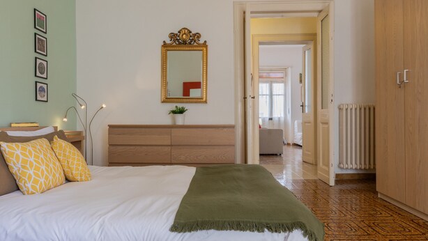 Une chambre à coucher comprenant un lit, une commode, un miroir et une porte donnant sur une autre pièce.