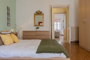 Une chambre à coucher comprenant un lit, une commode, un miroir et une porte donnant sur une autre pièce.