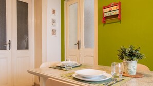Un coin repas avec une table dressée pour deux personnes, comprenant des assiettes, des couverts et des verres.