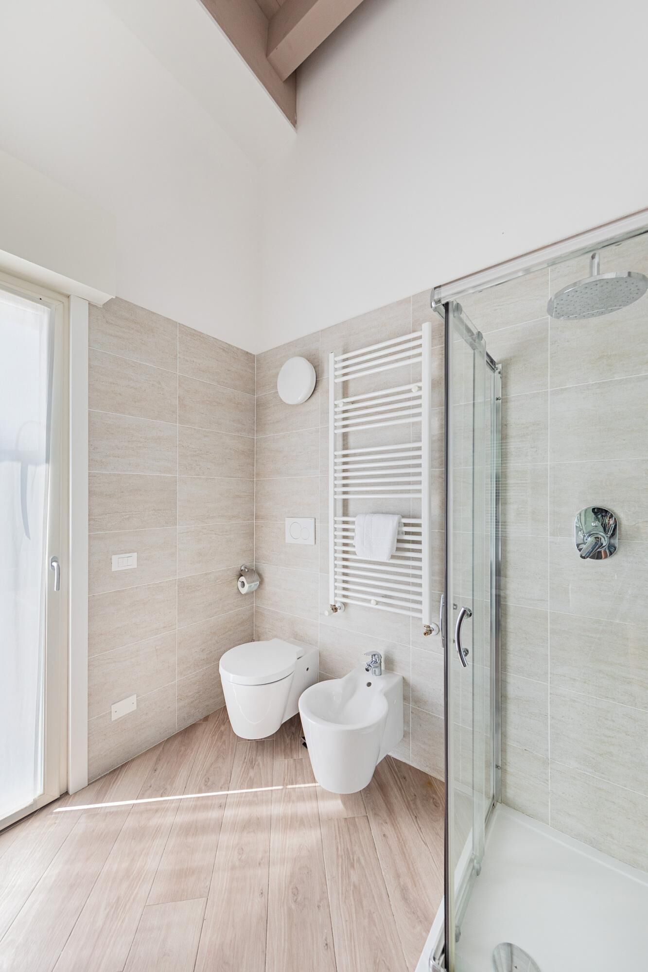 A modern bathroom with a glass shower enclosure, a toilet, bidet, and a sink.