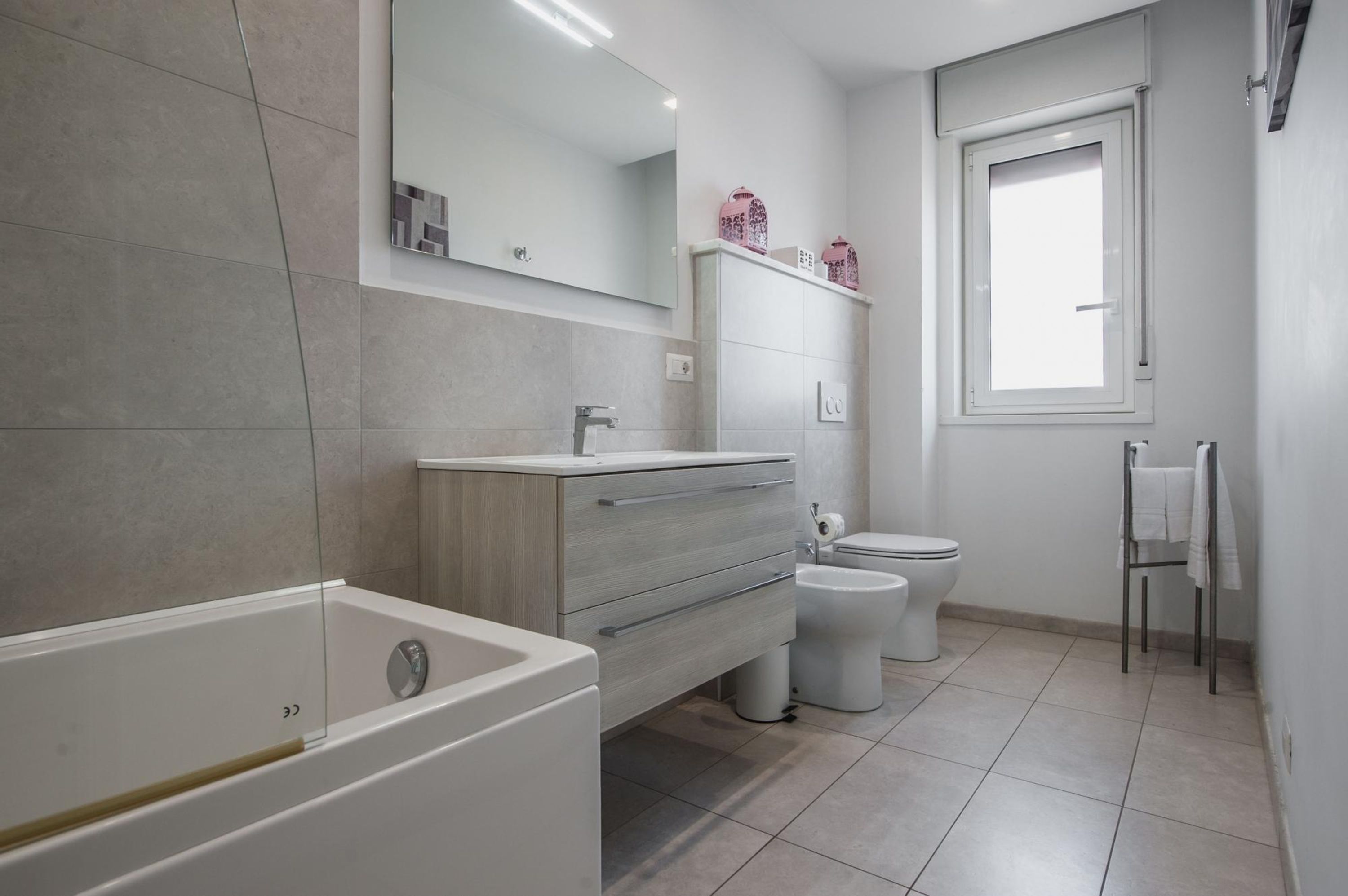 Une salle de bain moderne équipée d’une baignoire, d’un meuble-lavabo, de toilettes et d’un bidet.